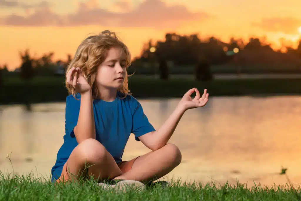 niño-meditando-postura-loto-lago