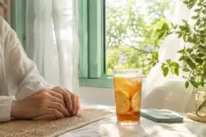 emotionally intelligent people shown by hands by a sunlit summer window with iced tea and a phone face down