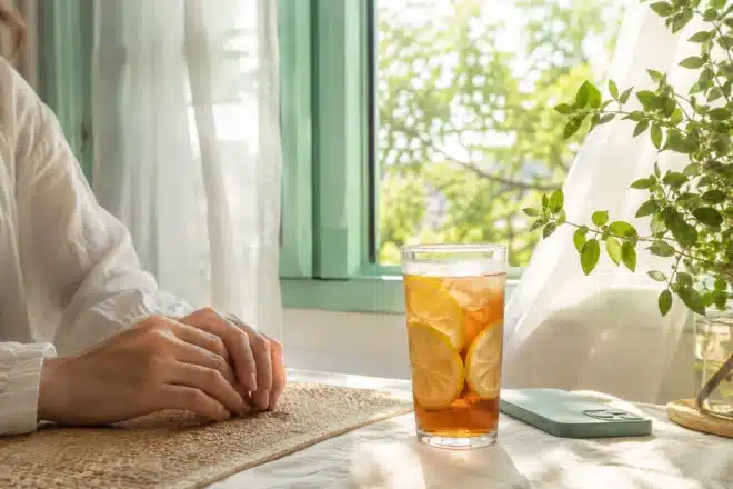 emotionally intelligent people shown by hands by a sunlit summer window with iced tea and a phone face down